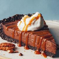 Slice of no-bake chocolate mousse pie drizzled with coconut whipped cream and caramel sauce