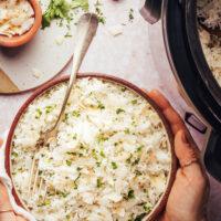 Hands holding a bowl of coconut rice made in the Instant Pot