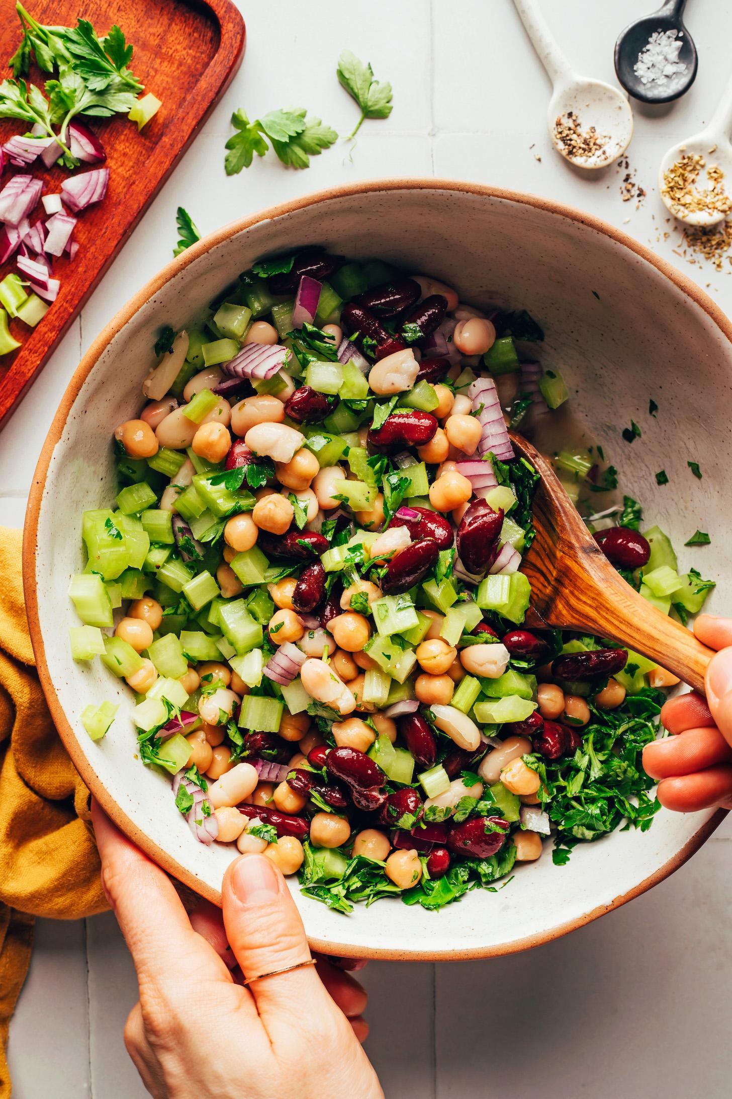 Stirring together a vinaigrette dressing with crunchy veggies, parsley, and beans