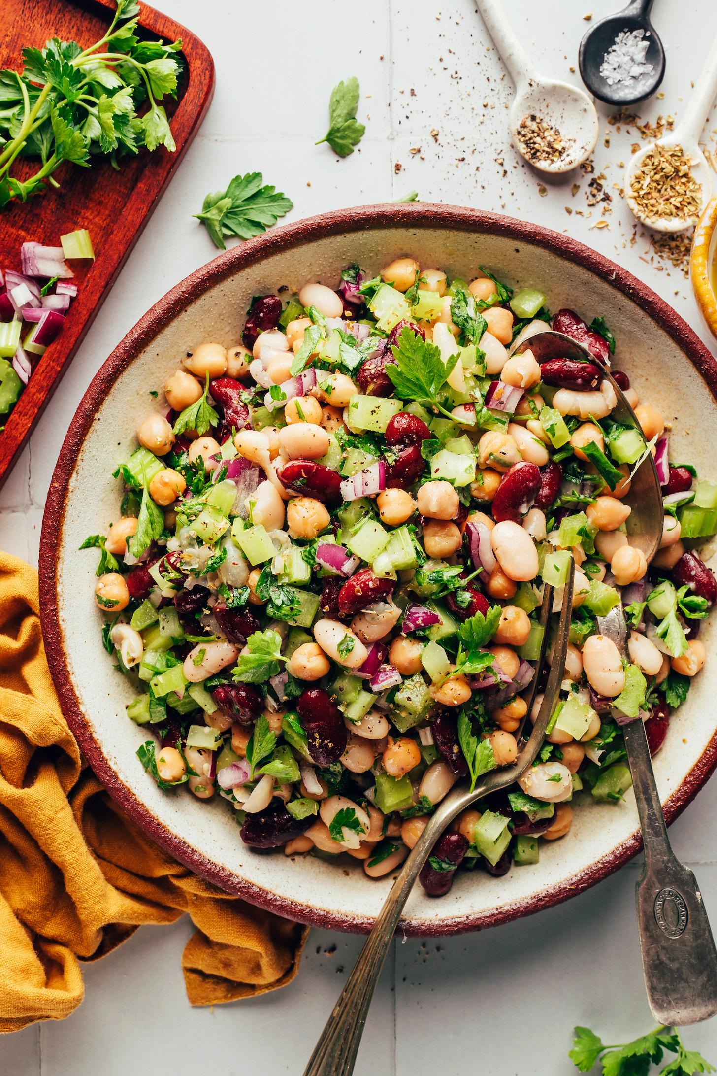 Spoon and fork resting in a bowl of Italian three bean salad