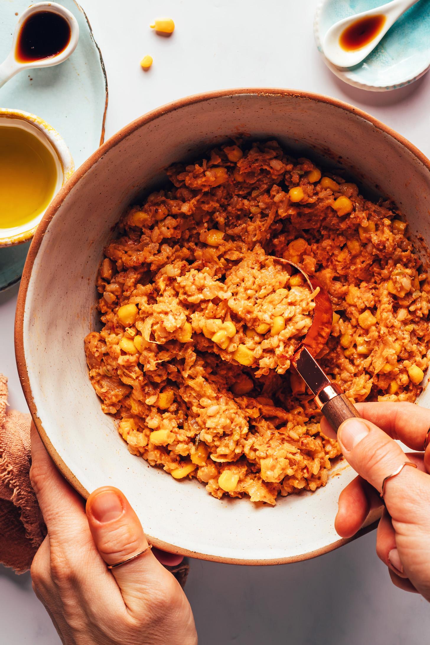 Using a measuring cup to scoop kimchi rice mixture from a bowl