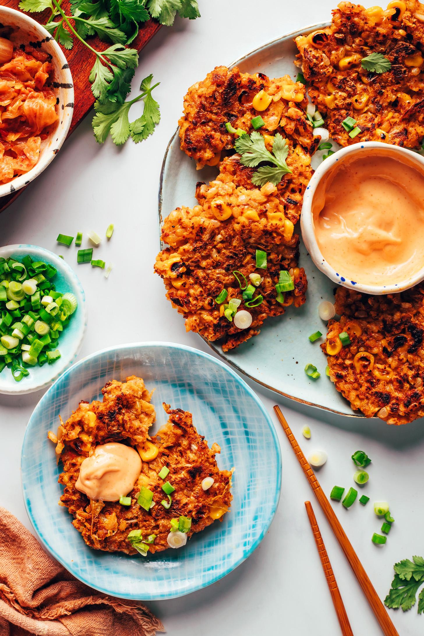 Plate and platter of kimchi rice fritters with sriracha sour cream in a bowl and next to it