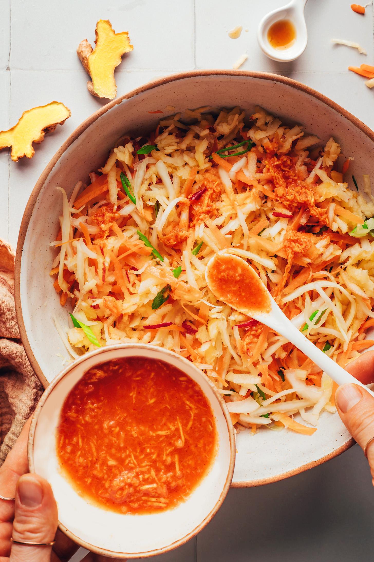 Using a spoon to add a garlicky, Korean-inspired dressing to the slaw