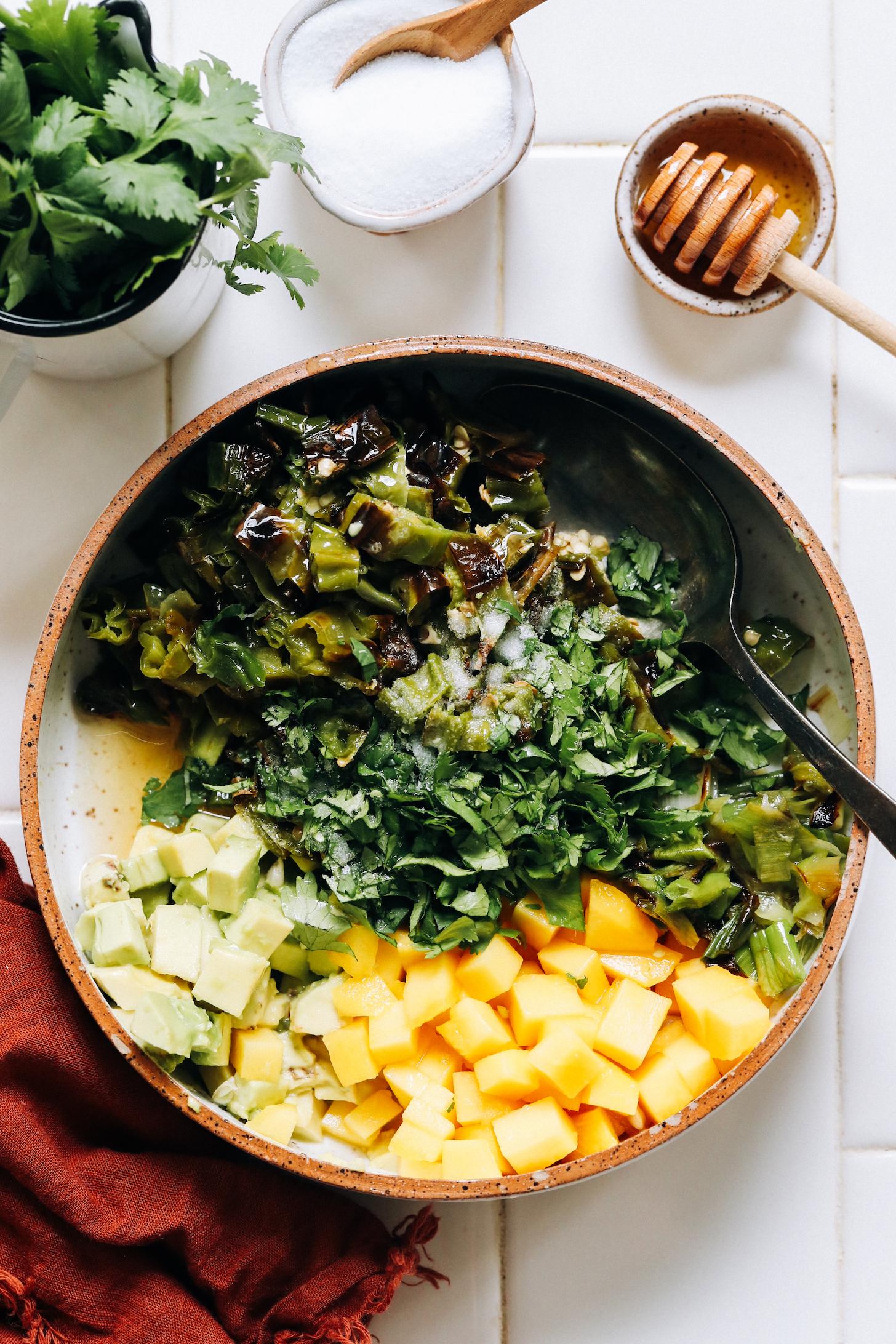 Bowl with chopped mango, avocado, cilantro, charred shishito peppers, and green onions