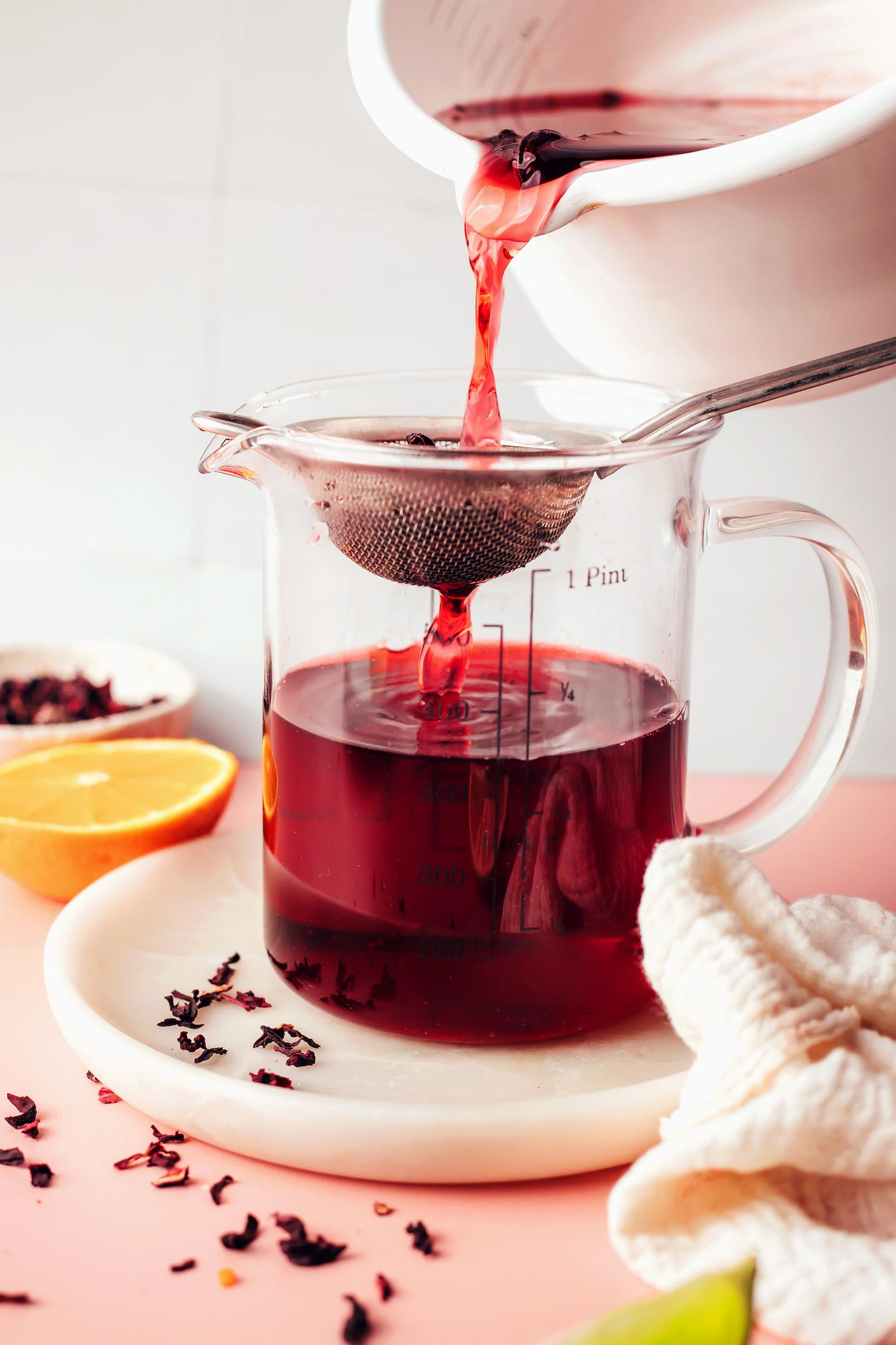 Straining hibiscus tea into a measuring glass