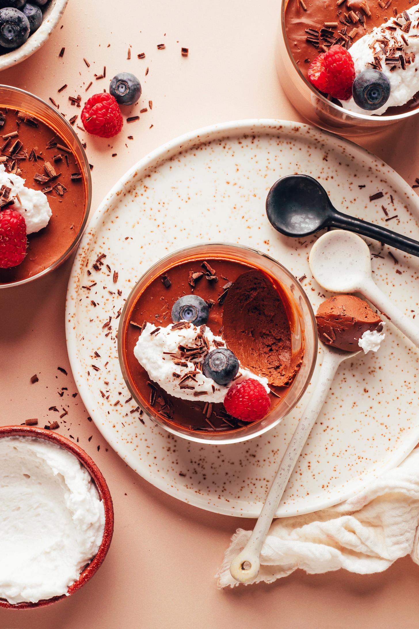 Chocolate pot de creme in small glasses topped with coconut whipped cream and fresh berries