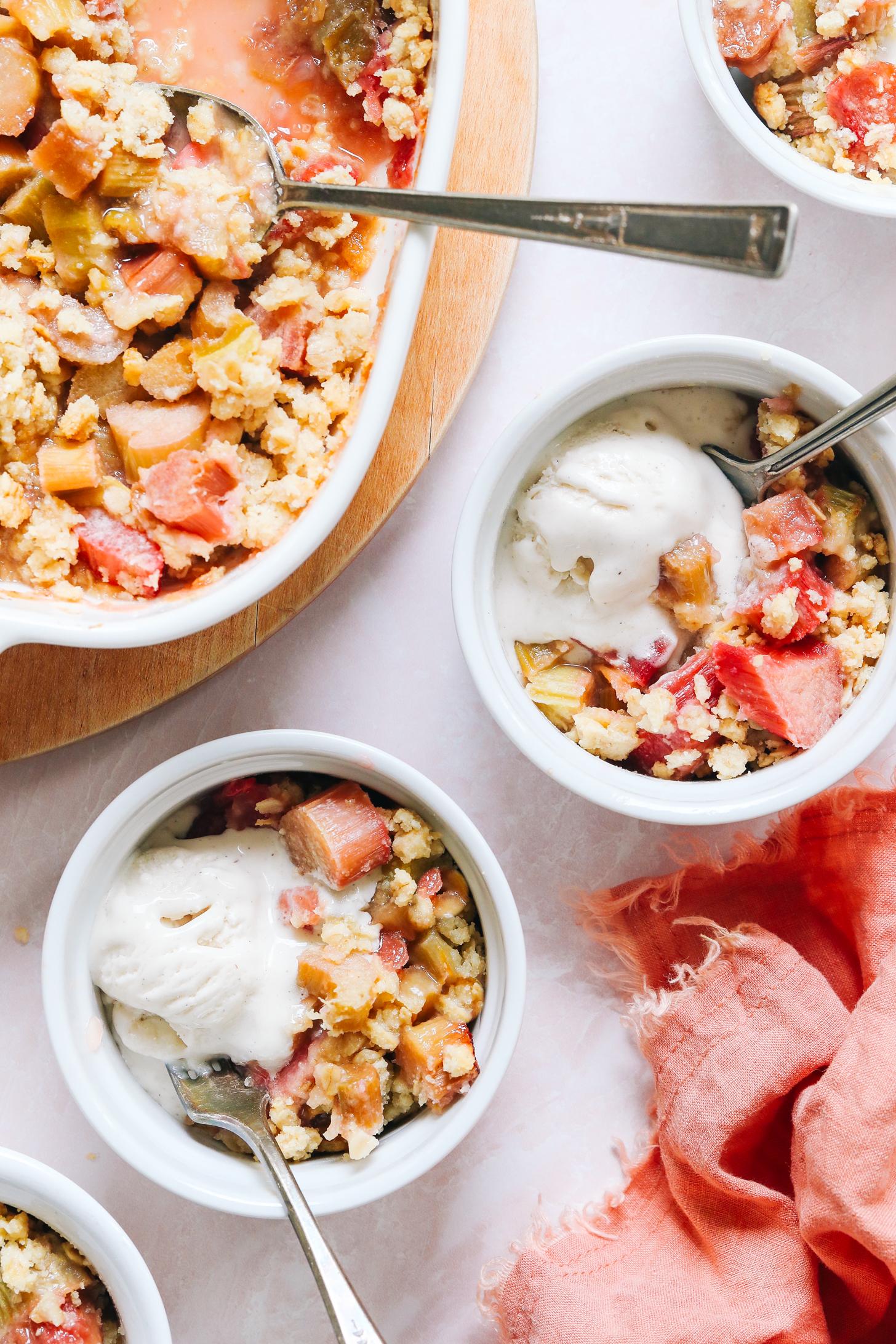 Serving bowls and baking dish of vegan gluten-free rhubarb crisp