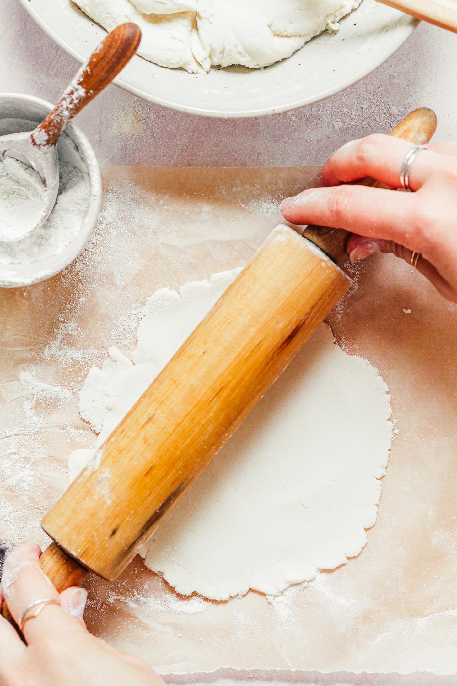 Rolling out a cassava flour tortilla with a rolling pin on a piece of parchment paper