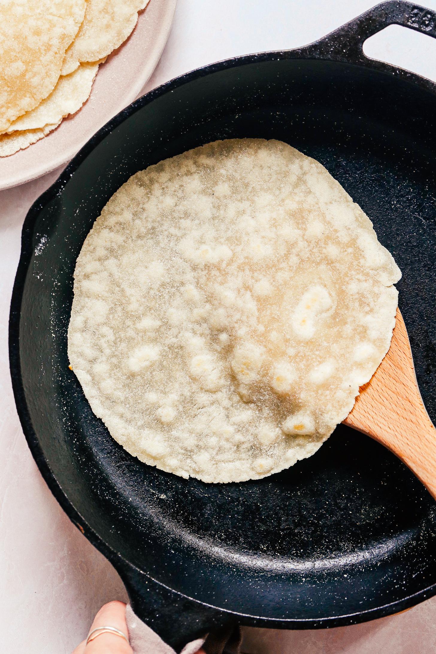 Flipping a cassava flour tortilla in a cast iron skillet