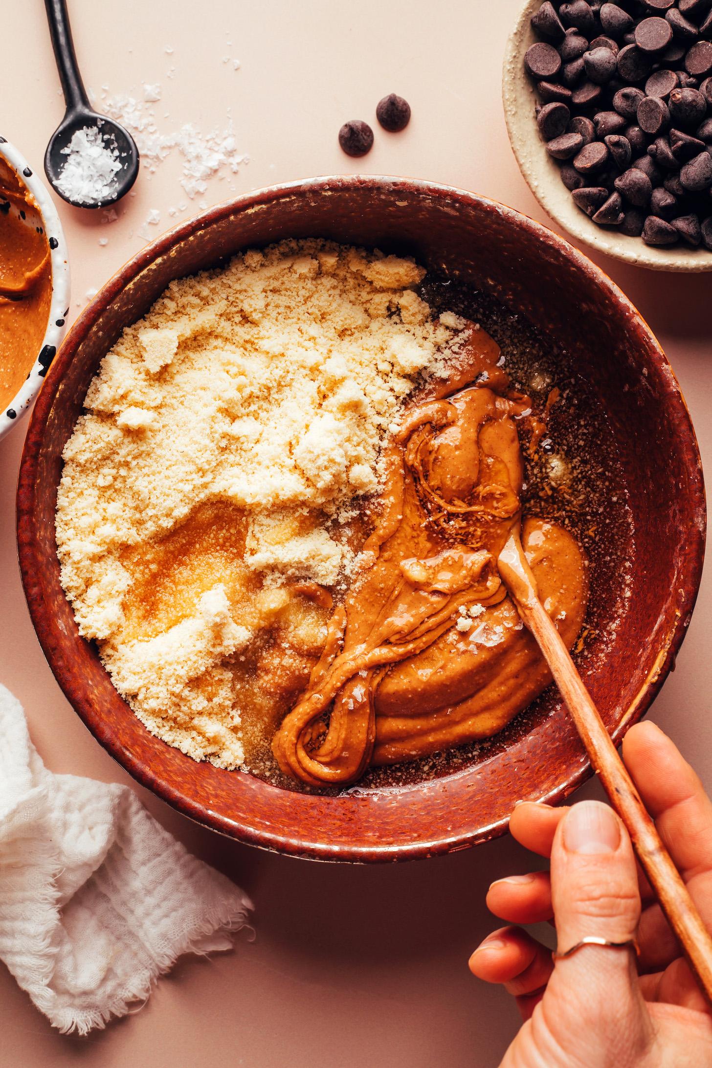 Stirring peanut butter, almond flour, maple syrup, and salt in a bowl