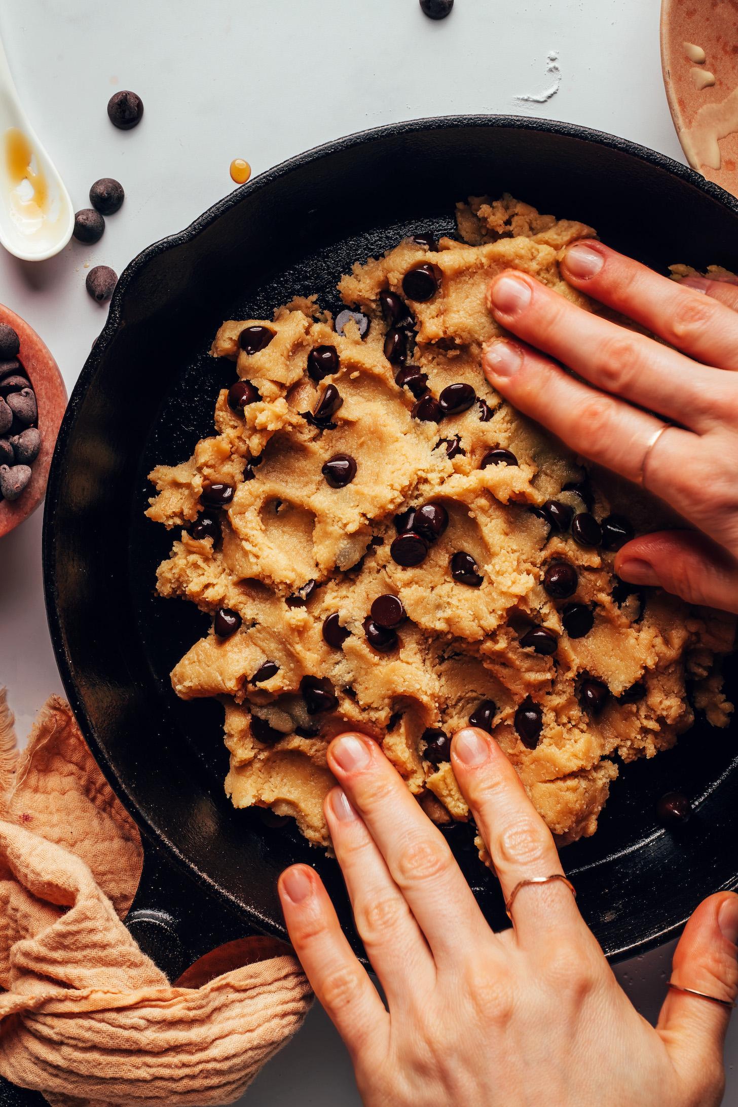 Spreading chocolate chip cookie dough into a cast iron skillet