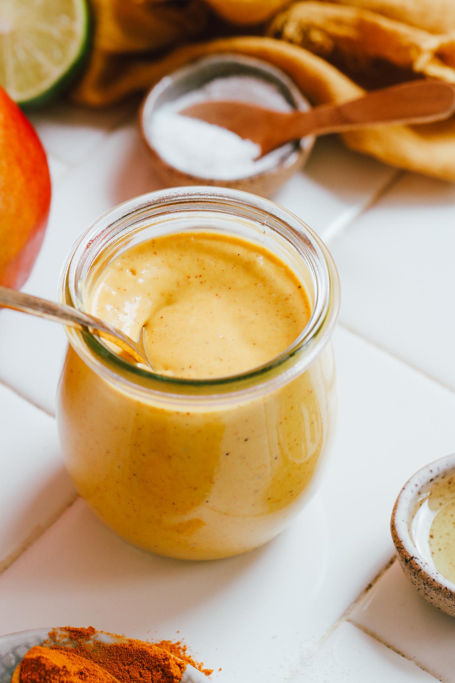 Spoon in a jar of creamy turmeric mango vinaigrette