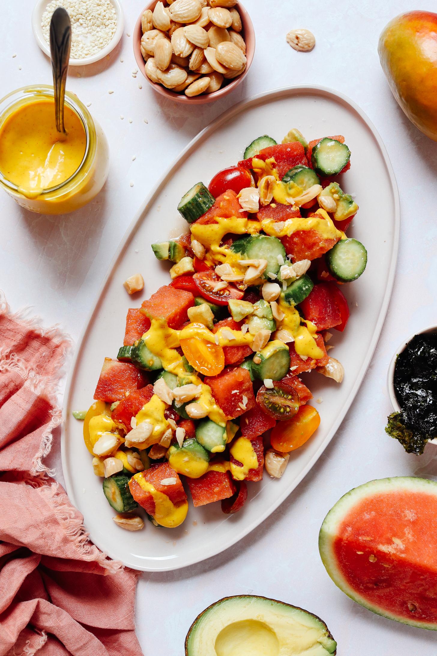 Overhead shot of a platter of watermelon cucumber salad topped with dressing and almonds