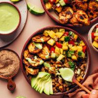 Drizzling a creamy green sauce onto Jerk Tofu & Roasted Plantain Bowls