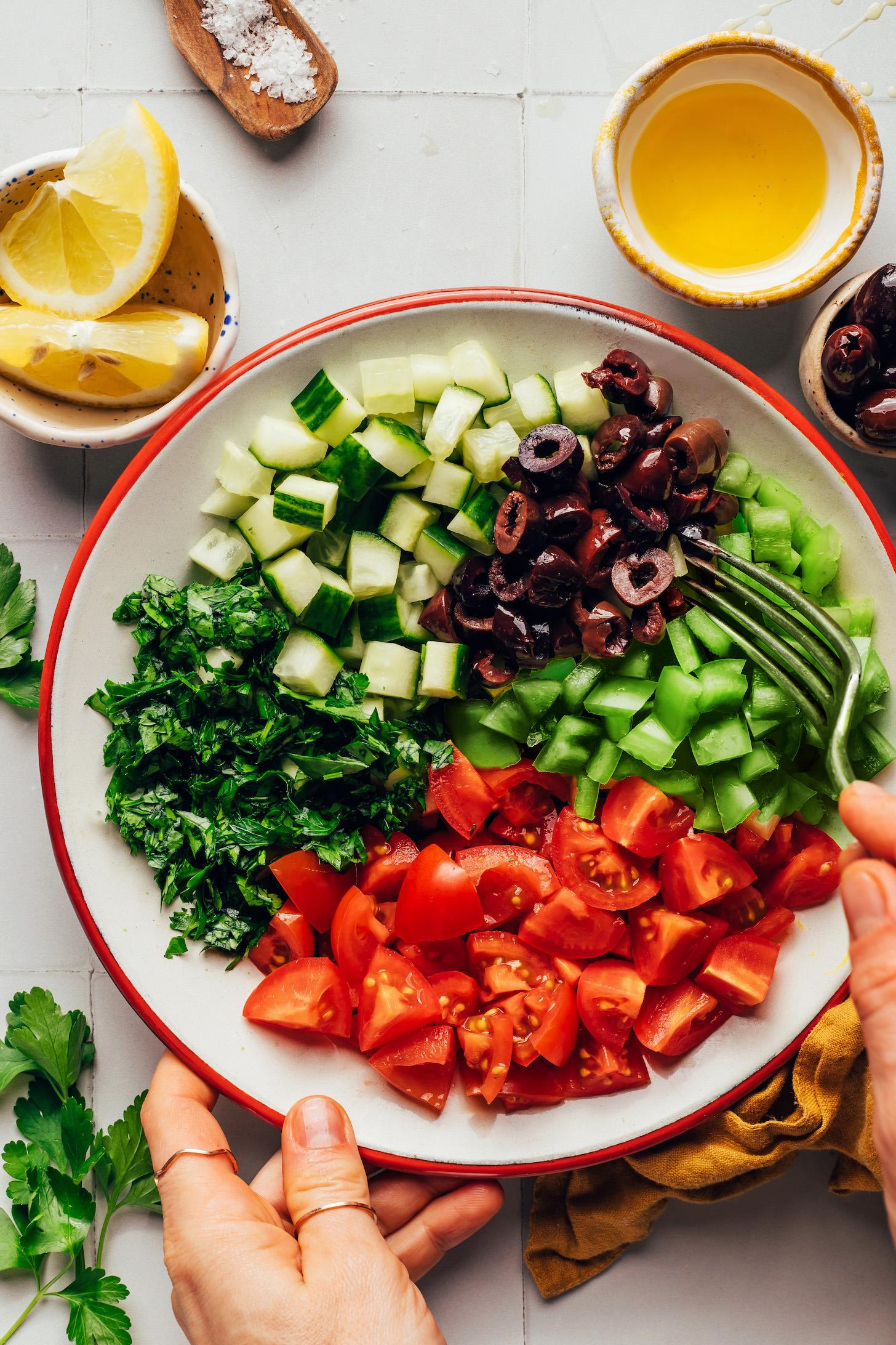 Bowl of chopped tomato, green bell pepper, kalamata olives, cucumber, and parsley