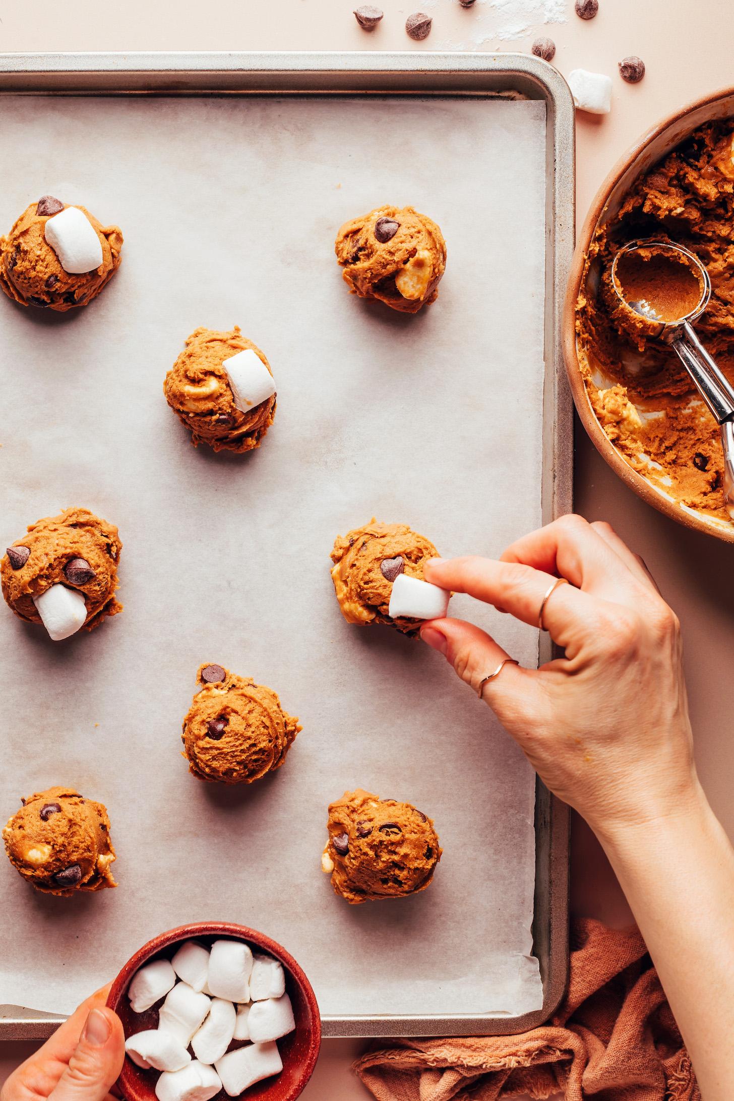 Putting a mini marshmallow on top of balls of cookie dough