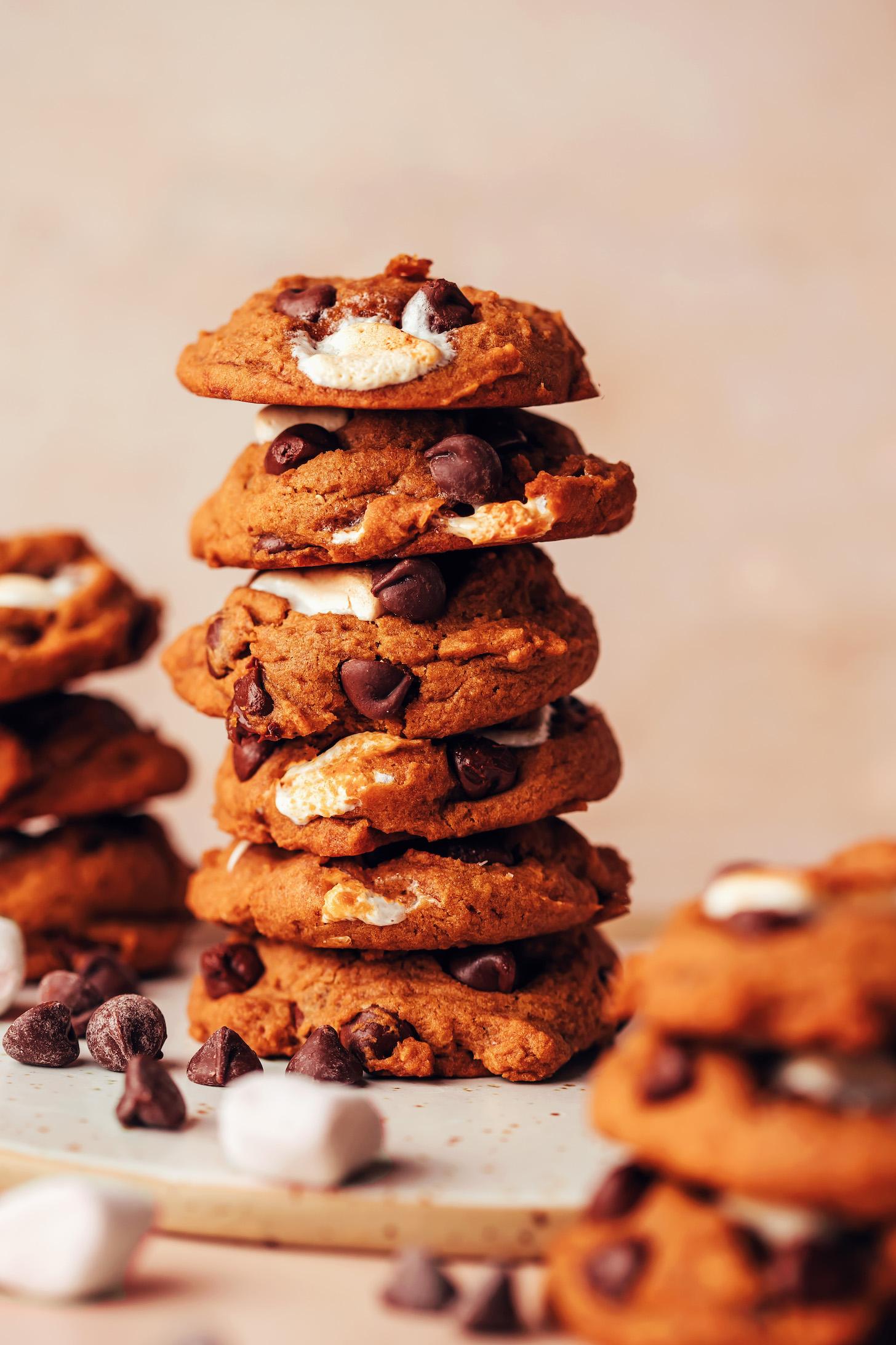 Stack of vegan s'mores cookies with marshmallows and chocolate chips next to them