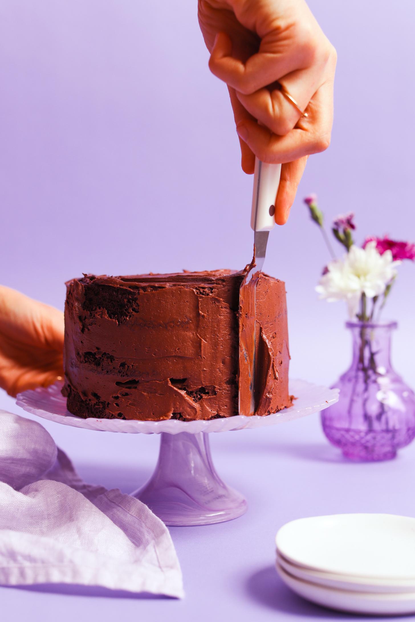 Using an offset spatula to frost a cake with vegan chocolate ganache frosting