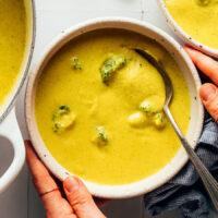 Close up shot of a bowl of vegan broccoli cheddar soup with chunks of broccoli