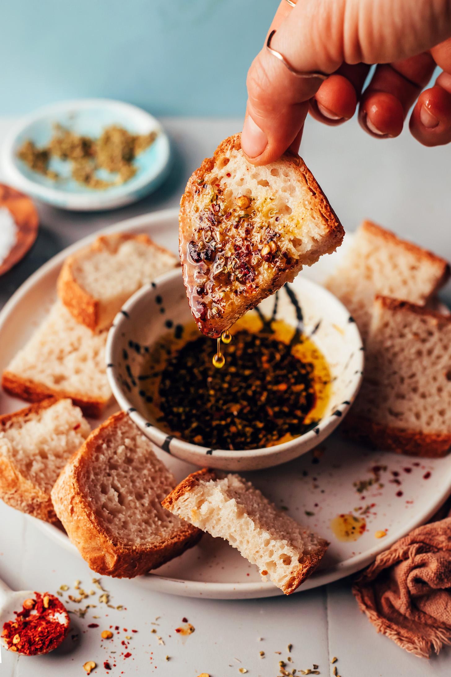 Holding a slice of gluten-free bread just dipped into an olive oil and balsamic vinegar dipping sauce