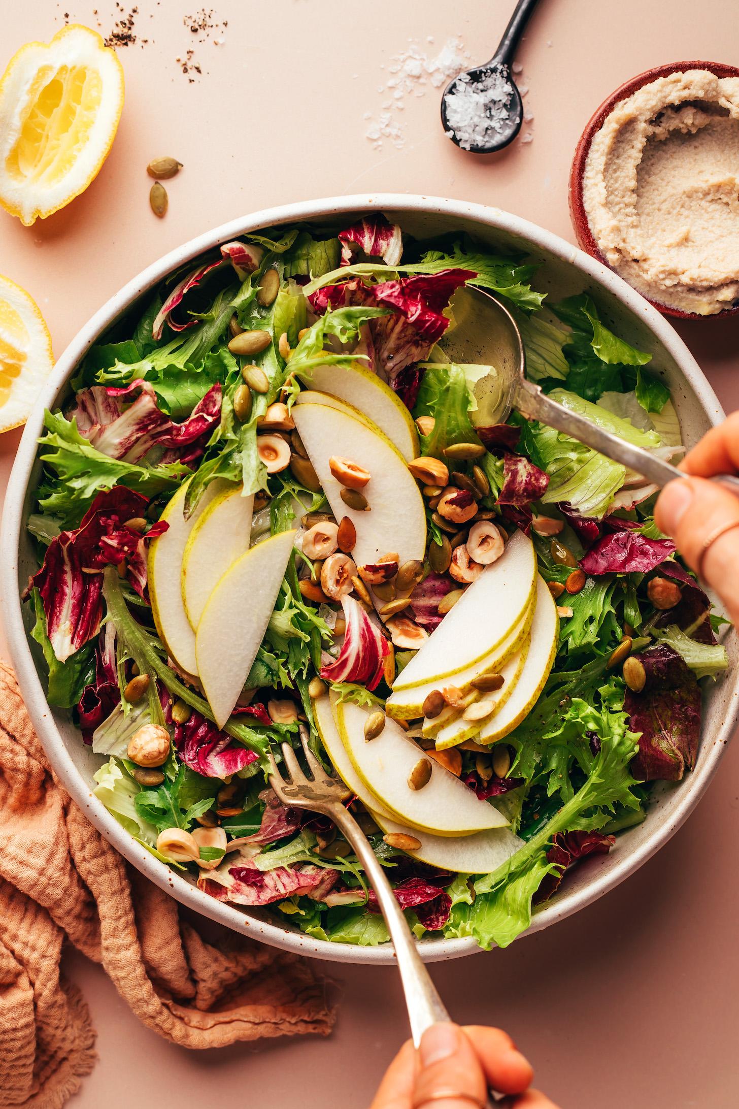 Using a serving spoon and fork to toss a salad