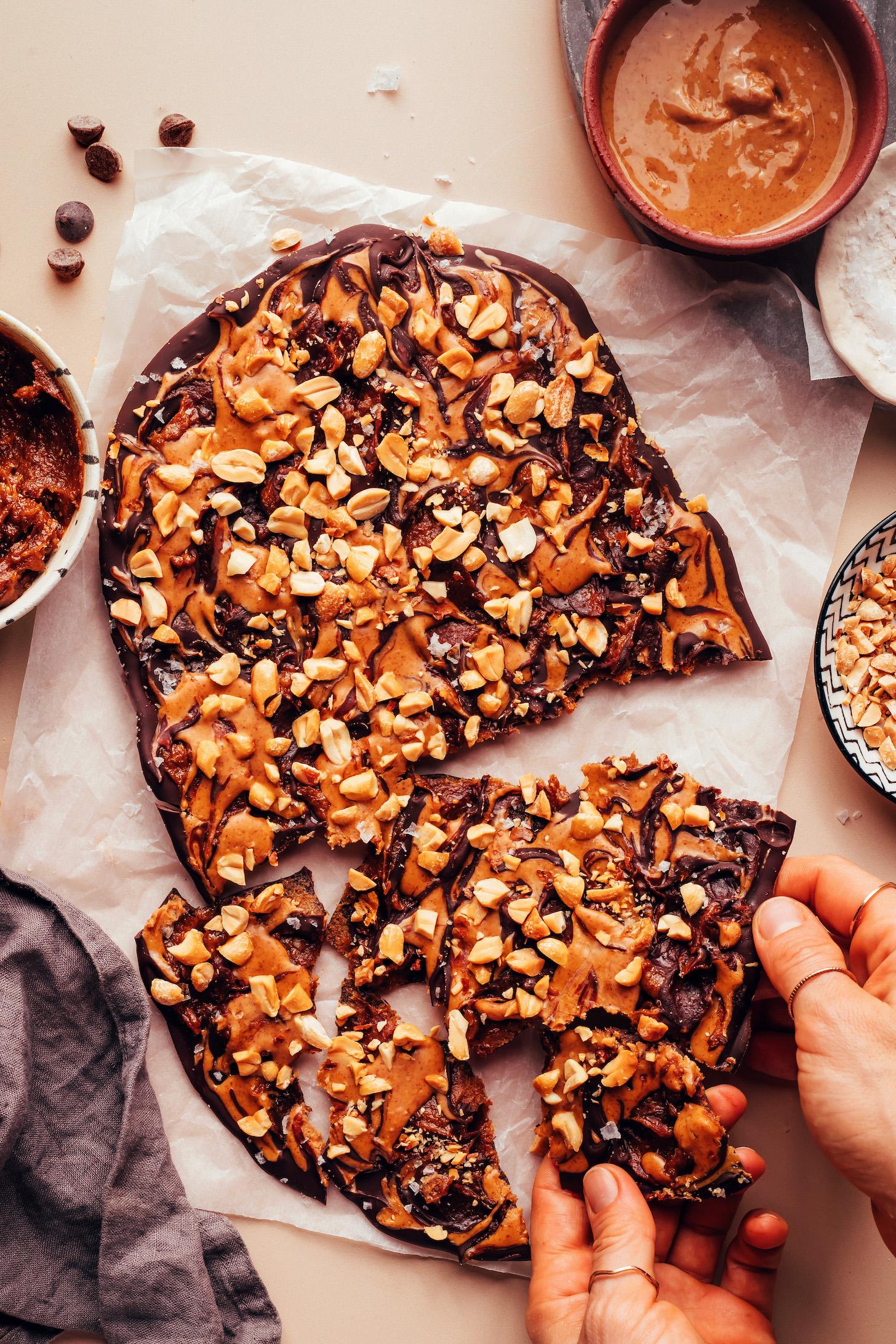 Pieces of date Snickers chocolate bark on a piece of parchment paper