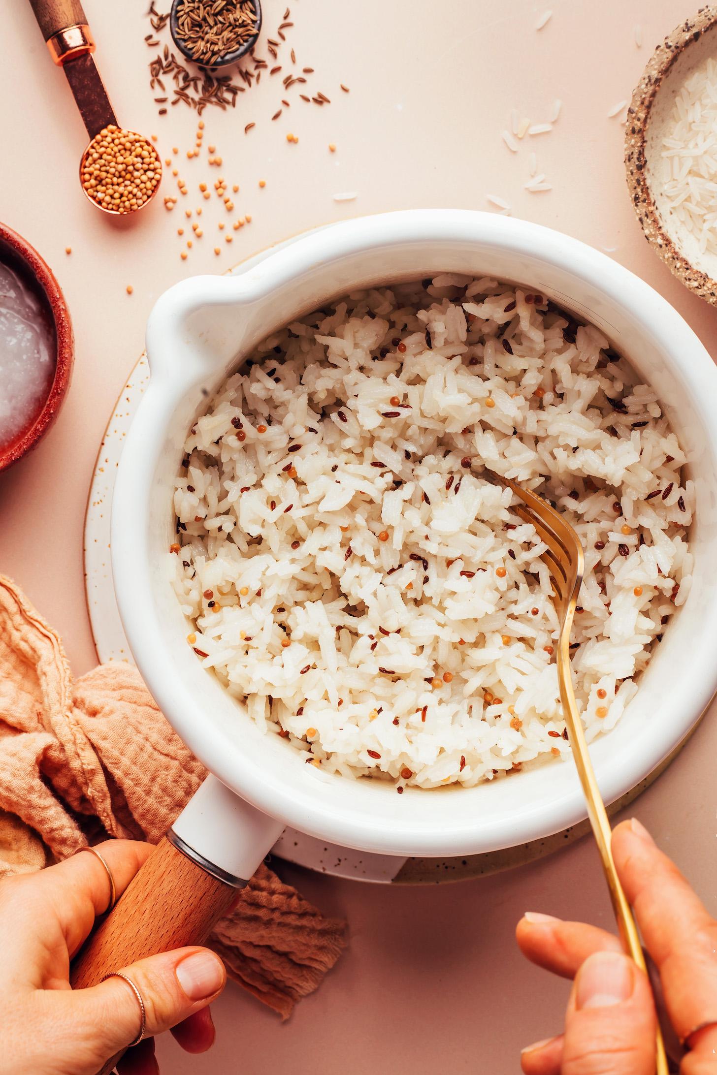 Using a fork to fluff a pan of fluffy vegan jeera rice