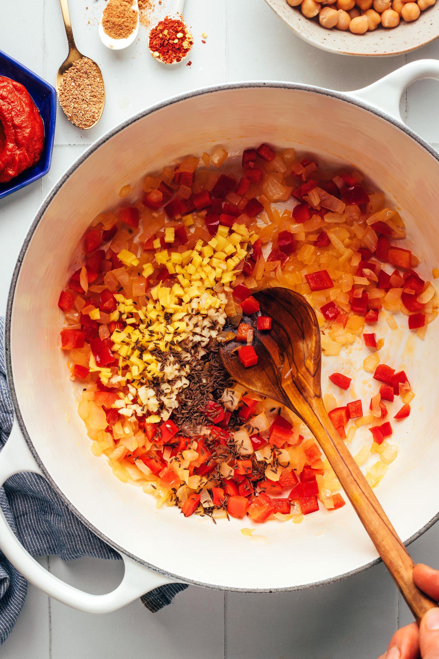 Minced ginger, garlic, and cumin seeds in a pot with sautéed onion and bell pepper