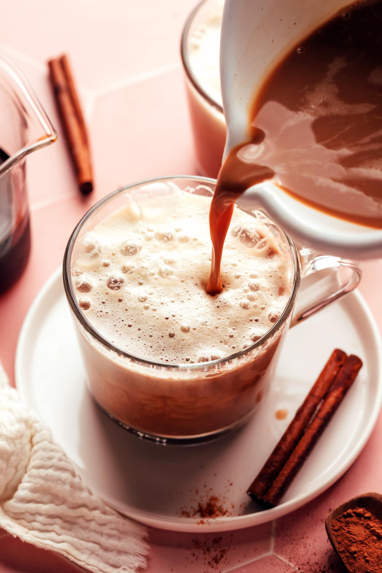 Pouring a frothy caffeine-free Mayan mocha drink into a glass mug