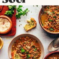 Slices of garlic bread in and next to bowls of Italian Lentil Soup also called Zuppa di Lenticchie