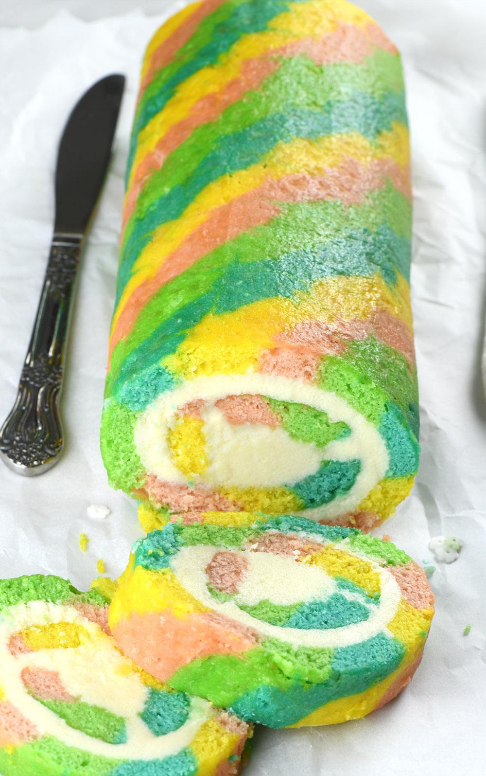 A whole multi-colored roll with two cut pieces in front