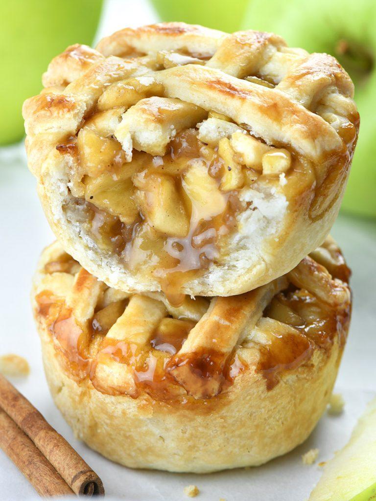 Two small slices of apple pie on top of each other. The top piece is bitten and will see the apple filling oozing out.