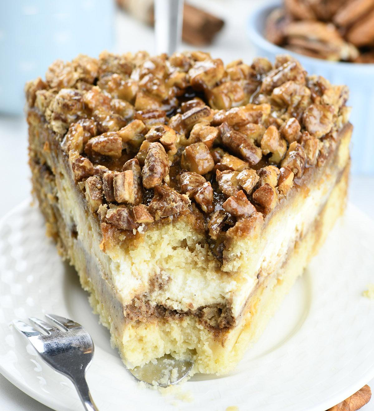 Piece of Pecan Pie Cheesecake Coffee Cake on a white plate  layered with flavorful cinnamon streusel crumbs.