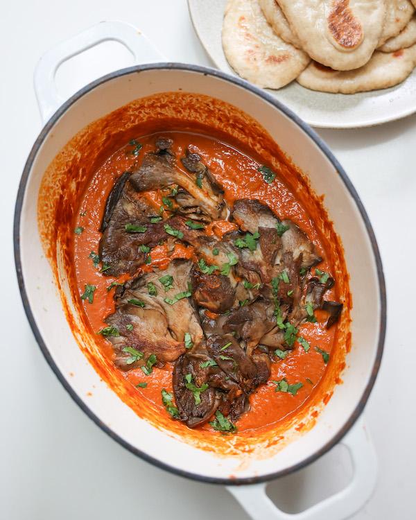 overhead of vegan butter chicken in a pot next to vegan naan flat bread