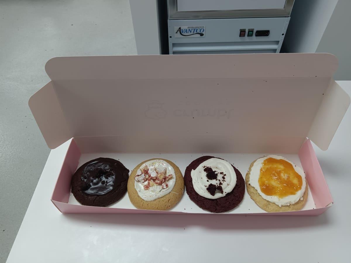 Four donuts in a pink box on a table.