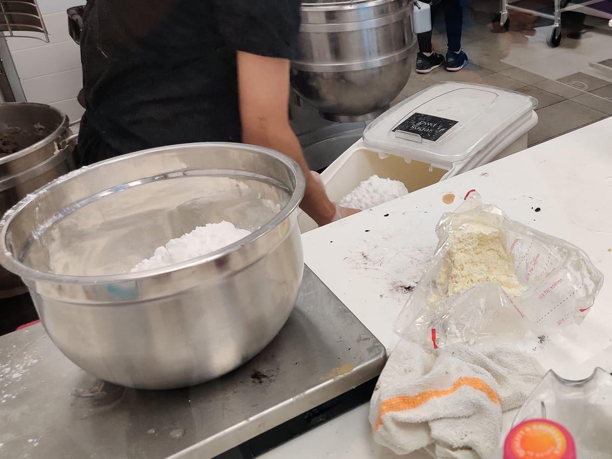 A person is mixing flour in a kitchen.