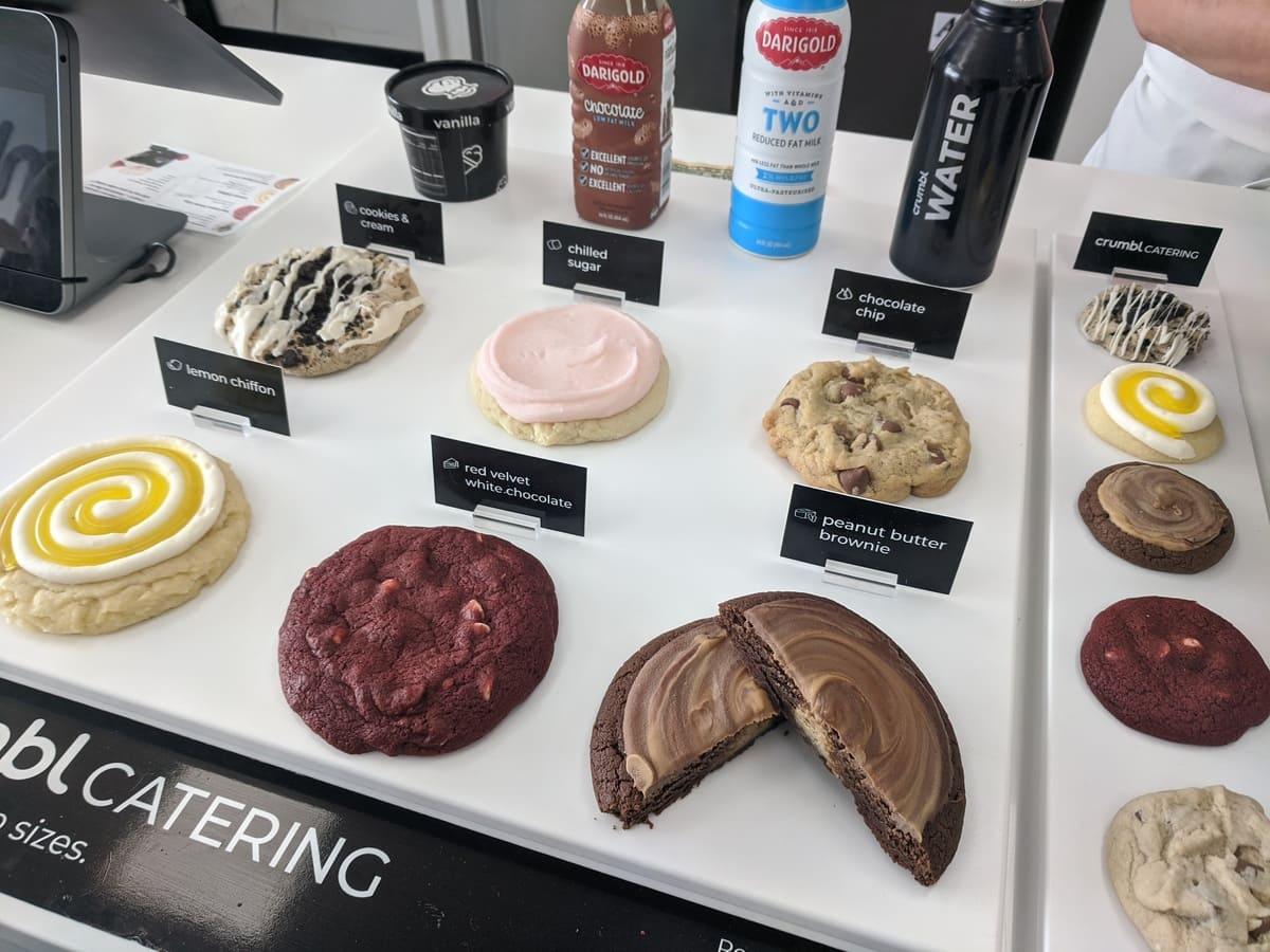 A display of Crumbl Cookies and other desserts on a table.