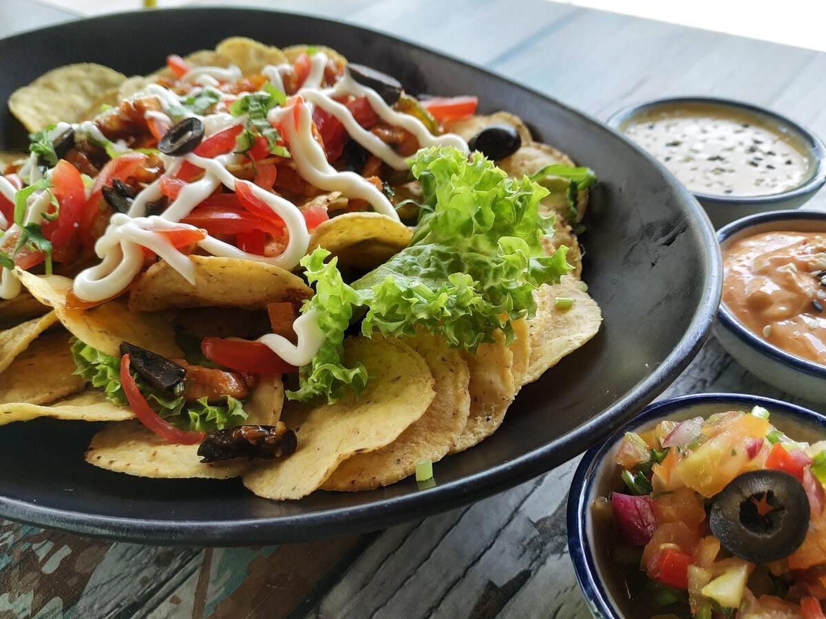 A bowl of nachos on a wooden table at Taco Bell during lunchtime.