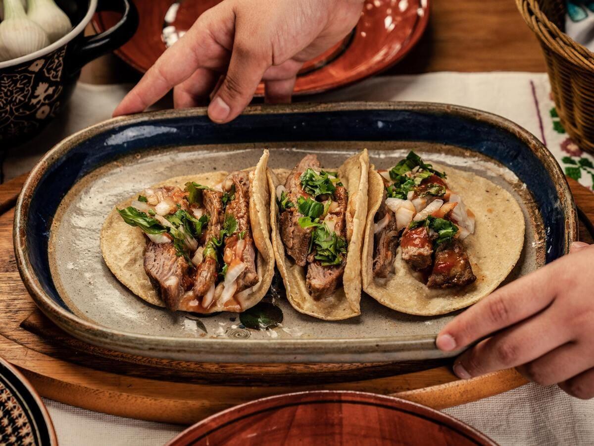 A person is serving tacos on a plate at Taco Bell.