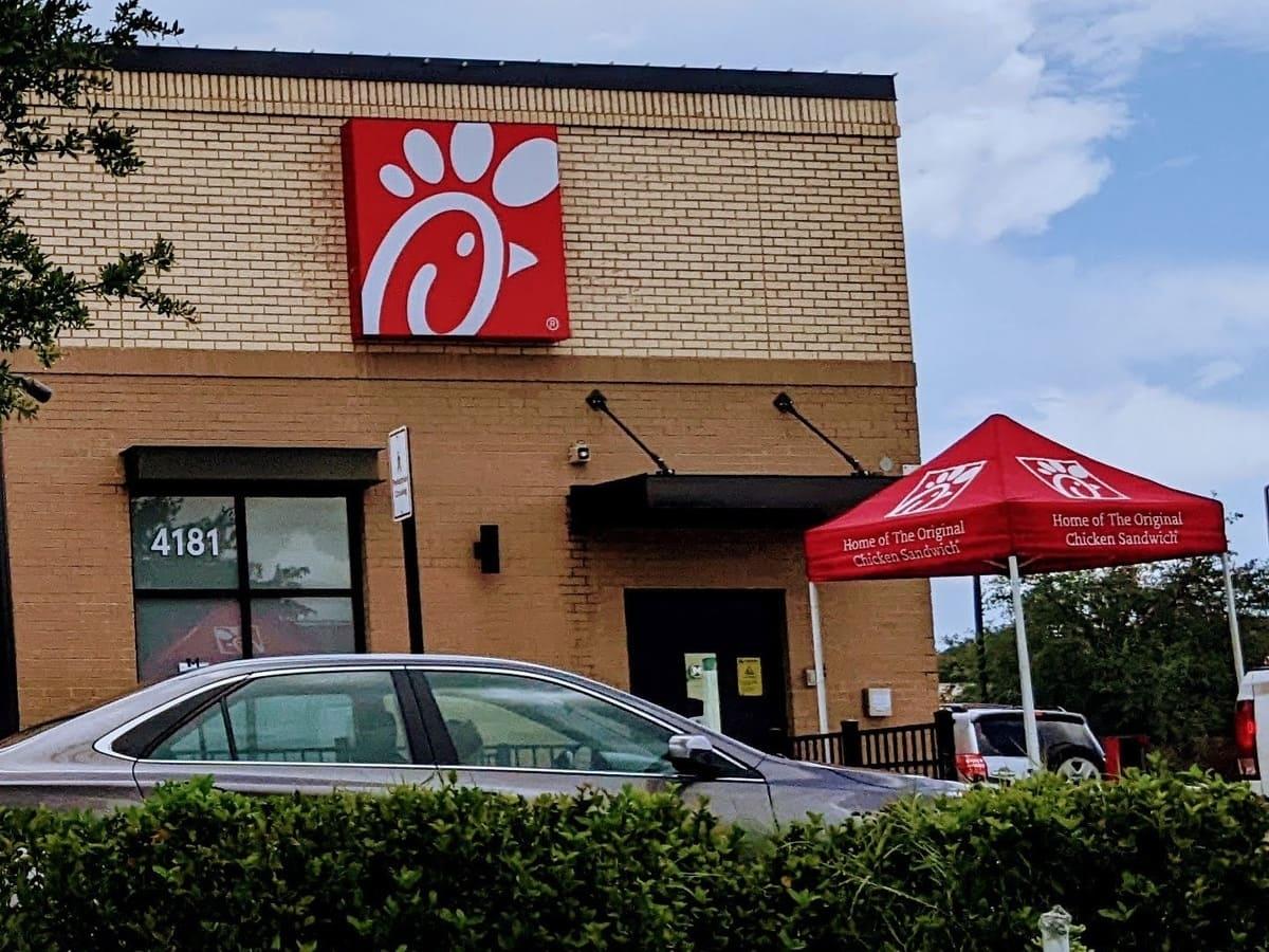 A fast food car is parked in front of a chicken wing restaurant.