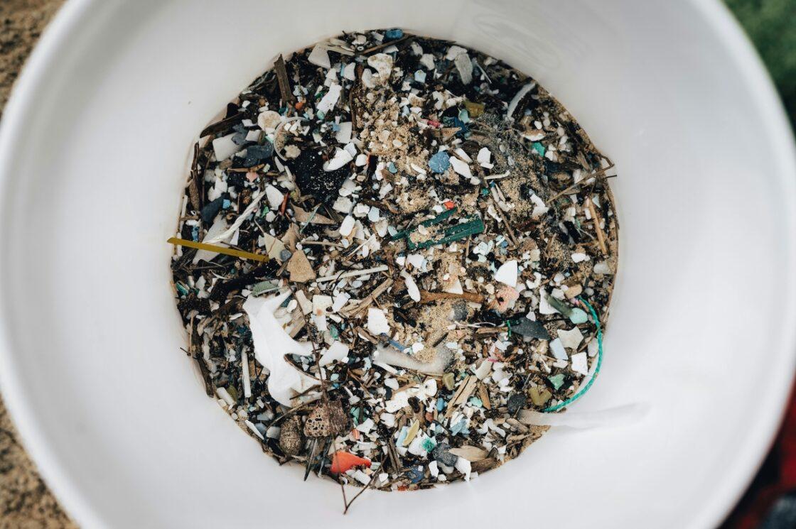 Image of a large plastic bucket filled with tiny bits of plastic debris of varying sizes and colors. How much microplastic do we consume?