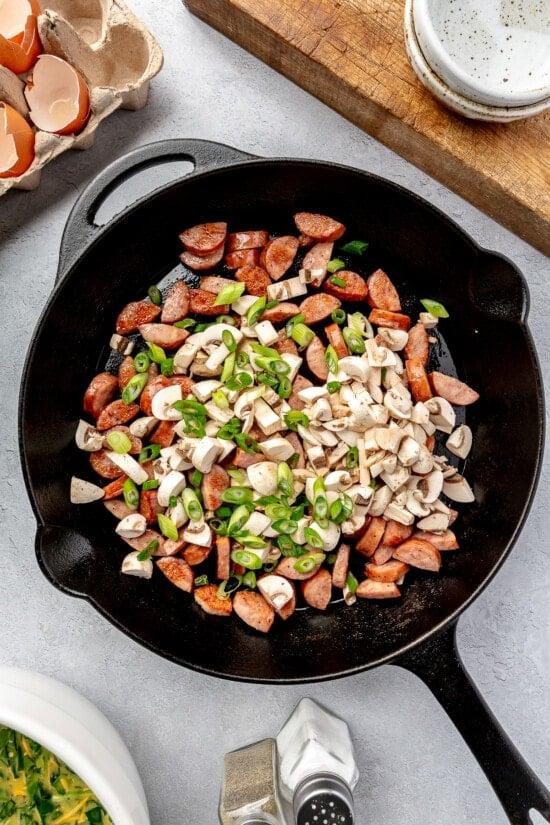 Skillet with smoked sausage, spinach, and mushrooms.