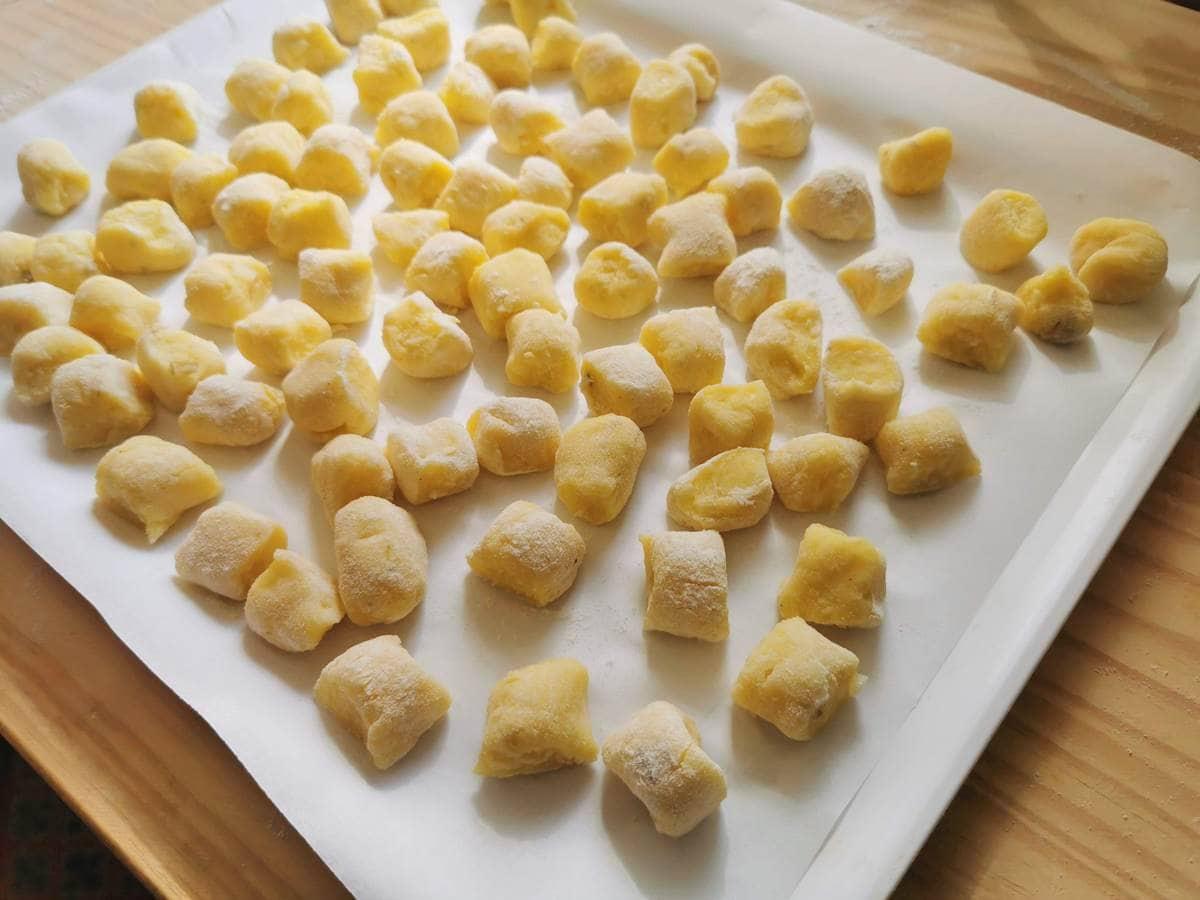 Ready homemade potato gnocchi on flour dusted parchment paper.