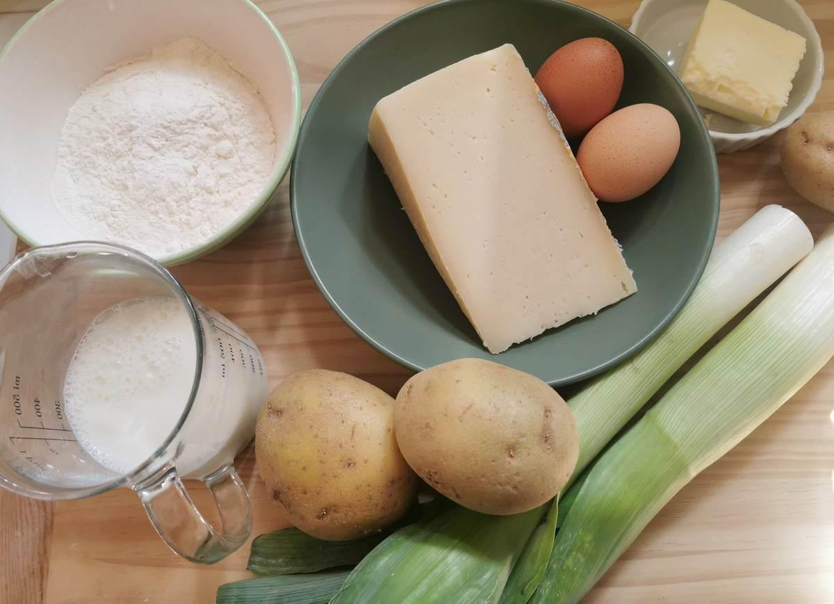 Ingredients for cheesy potato gnocchi; potatoes, eggs, flour, montasio cheese, leeks and milk.