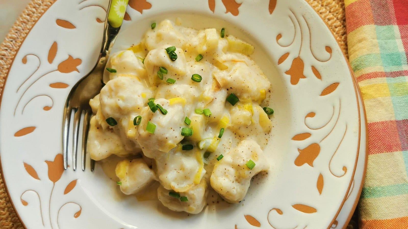 Ready plated homemade potato gnocchi with cheese and leek sauce and a sprinkling of chives.