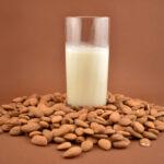 sprouted almond milk in a glass with raw almonds on table