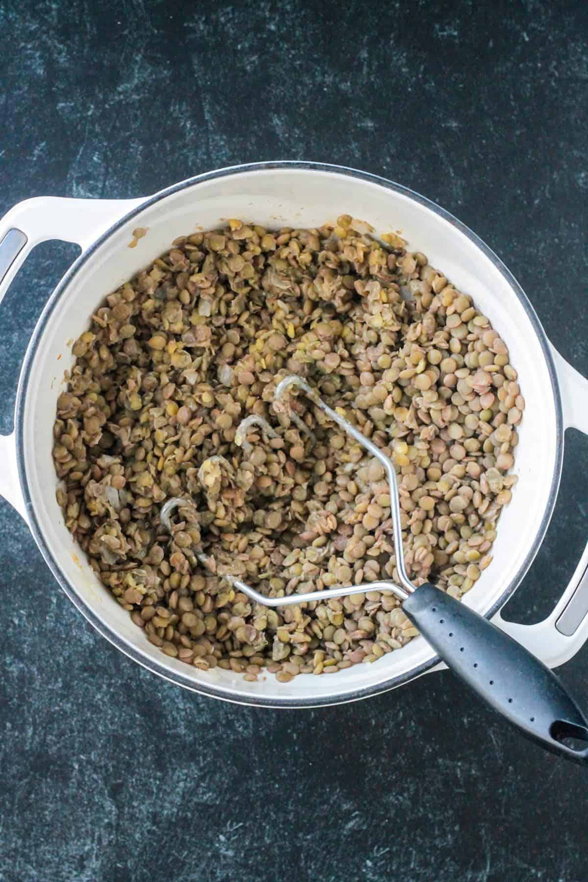 Cooked and mashed brown lentils in a pot.