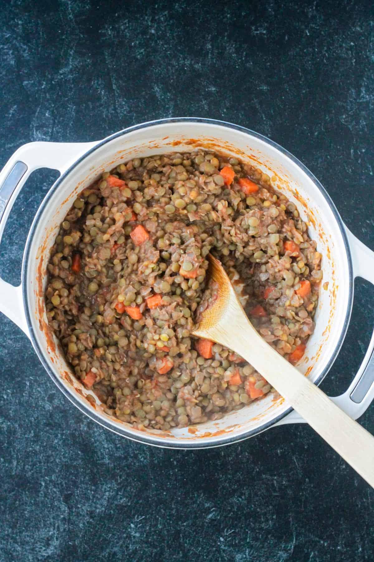 Cooked lentils mixed with spices and carrots in a pot.