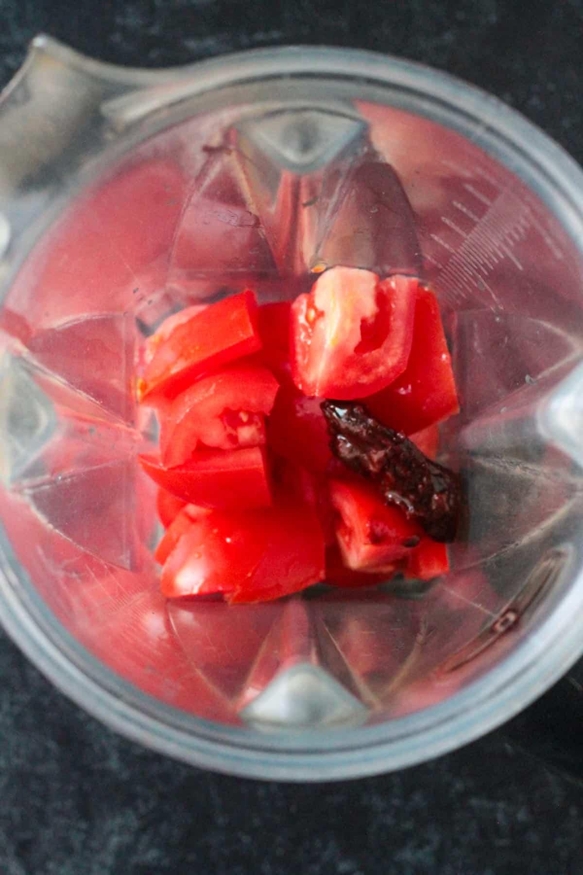 Chopped roma tomatoes in a blender with a chipotle in adobo.